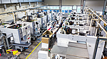 Bird's eye view of a large production hall with numerous white EMAG lathes in rows, demonstrating the extensive production capacity of PENN GmbH with a total of 43 spindles.