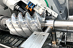 View into the work area of the CLC 500 H FR during the machining of a rotor. The powerful profile milling head mills the rotor profile with high precision. The picture shows the flexibility of the machine and the possibility of realizing large spiral angles. 