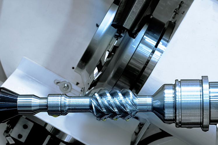 Work area of an EMAG profile milling machine with a milling tool. The machine is machining a rotor with a complex helical profile. 