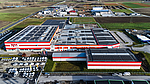 Aerial view of the PENN GmbH industrial complex in Stratzdorf with several modern production buildings and red and white façade elements, surrounded by parking lots and agricultural land.