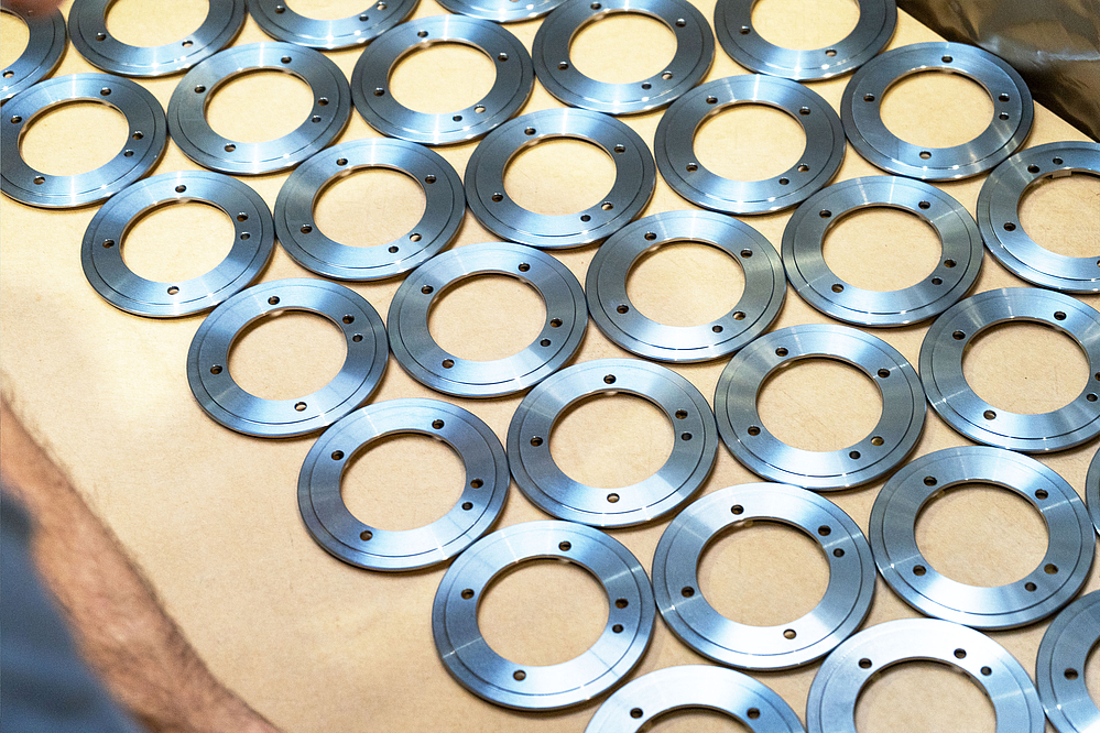 Rows of evenly arranged, precision machined, ring-shaped metal components on a light-colored base, ready for delivery to the automotive industry.