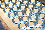 Rows of evenly arranged, precision machined, ring-shaped metal components on a light-colored base, ready for delivery to the automotive industry.